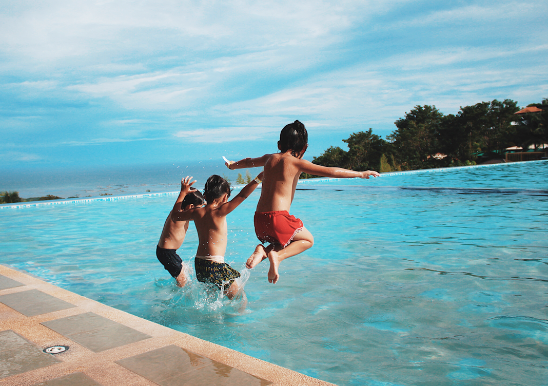 3 enfants qui sautent dans une piscine